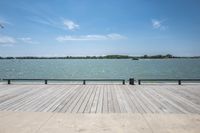 an empty wooden pier with view of water and trees in the distance area of the area