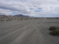 a wide empty dirt road in front of a high desert area in the foreground