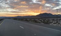 an open highway with mountains and hills in the distance at sunset in the desert setting