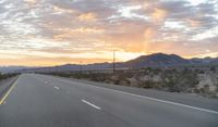 an open highway with mountains and hills in the distance at sunset in the desert setting