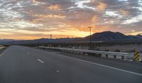 an open highway with mountains and hills in the distance at sunset in the desert setting