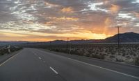 an open highway with mountains and hills in the distance at sunset in the desert setting