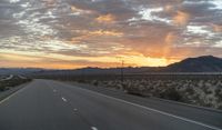 an open highway with mountains and hills in the distance at sunset in the desert setting