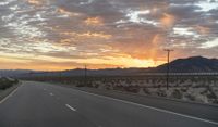 an open highway with mountains and hills in the distance at sunset in the desert setting