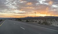 an open highway with mountains and hills in the distance at sunset in the desert setting