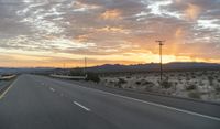 an open highway with mountains and hills in the distance at sunset in the desert setting