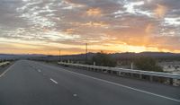 an open highway with mountains and hills in the distance at sunset in the desert setting