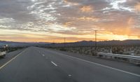 an open highway with mountains and hills in the distance at sunset in the desert setting