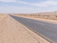 empty road near desert area with mountains in background, no people yet on it, in the distance are bushes and sparse clouds