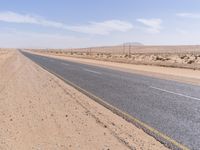 empty road near desert area with mountains in background, no people yet on it, in the distance are bushes and sparse clouds