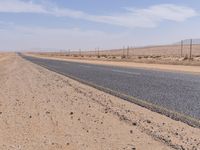 empty road near desert area with mountains in background, no people yet on it, in the distance are bushes and sparse clouds