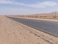 empty road near desert area with mountains in background, no people yet on it, in the distance are bushes and sparse clouds