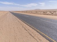 empty road near desert area with mountains in background, no people yet on it, in the distance are bushes and sparse clouds