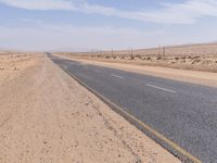 empty road near desert area with mountains in background, no people yet on it, in the distance are bushes and sparse clouds