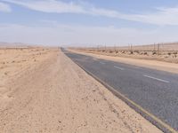 empty road near desert area with mountains in background, no people yet on it, in the distance are bushes and sparse clouds