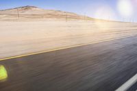 a motorcycle driving on a desert road near a mountain area, viewed from the window of an approaching car