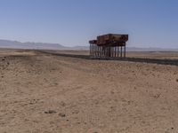 two long building stand alone in the middle of a desert field as people look on