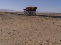 two long building stand alone in the middle of a desert field as people look on