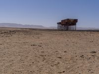 two long building stand alone in the middle of a desert field as people look on