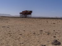 two long building stand alone in the middle of a desert field as people look on