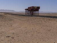 two long building stand alone in the middle of a desert field as people look on