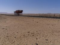 two long building stand alone in the middle of a desert field as people look on