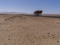 two long building stand alone in the middle of a desert field as people look on