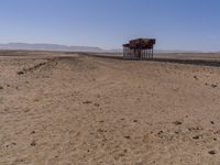 two long building stand alone in the middle of a desert field as people look on