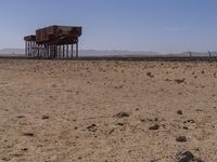 two long building stand alone in the middle of a desert field as people look on