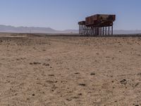 two long building stand alone in the middle of a desert field as people look on