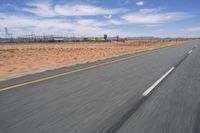 a desert landscape with the road in between it and two yellow lines on the side of the road