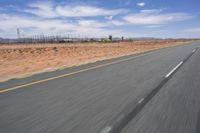 a desert landscape with the road in between it and two yellow lines on the side of the road