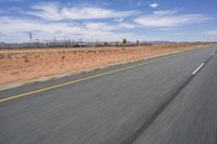 a desert landscape with the road in between it and two yellow lines on the side of the road