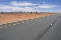 a desert landscape with the road in between it and two yellow lines on the side of the road