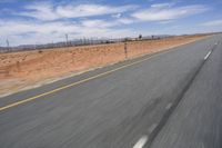 a desert landscape with the road in between it and two yellow lines on the side of the road