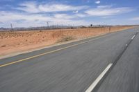 a desert landscape with the road in between it and two yellow lines on the side of the road