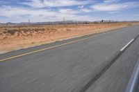 a desert landscape with the road in between it and two yellow lines on the side of the road