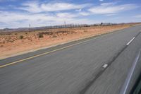 a desert landscape with the road in between it and two yellow lines on the side of the road