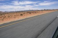 a desert landscape with the road in between it and two yellow lines on the side of the road