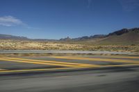 a desert with a curving road with mountains in the background in the background is a mountain range