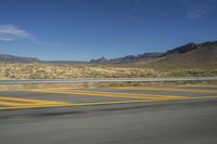 a desert with a curving road with mountains in the background in the background is a mountain range