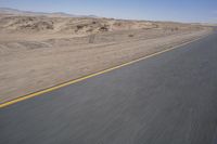 a motorcycle is driving on the road in the desert on a nice, sunny day