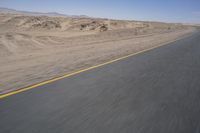 a motorcycle is driving on the road in the desert on a nice, sunny day