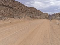 a small vehicle traveling across a barren road between some large rocks and boulders on one side