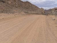 a small vehicle traveling across a barren road between some large rocks and boulders on one side