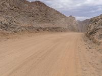 a small vehicle traveling across a barren road between some large rocks and boulders on one side