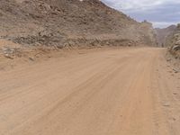 a small vehicle traveling across a barren road between some large rocks and boulders on one side