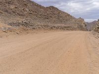 a small vehicle traveling across a barren road between some large rocks and boulders on one side