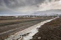 the snow line is white in color and dark clouds in background with rocks and snow