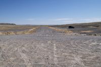 a truck that is parked on a dirt road in a barren landscape with tall grass